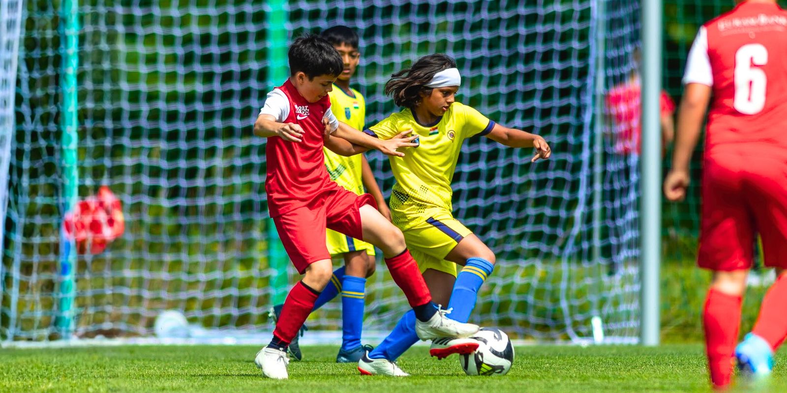 Two young players battling for the ball in front of goal