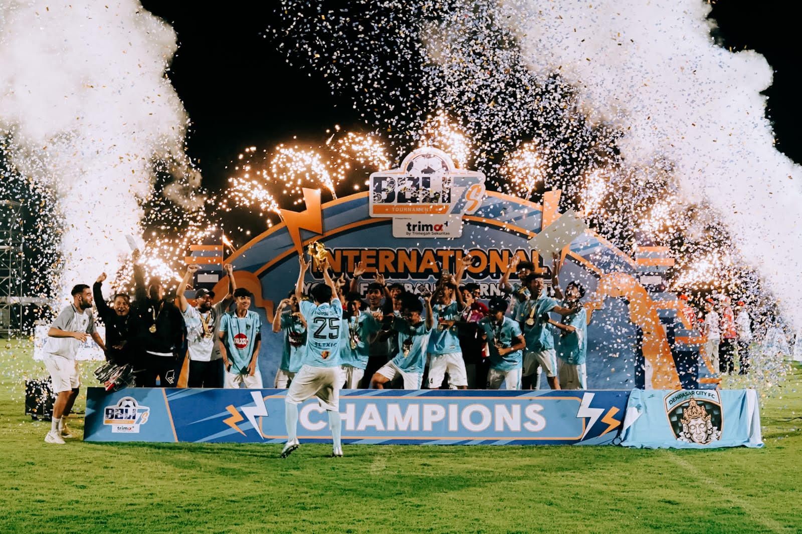 A team lifting the trophy on the BALI7s Champions stage with fireworks and confetti
